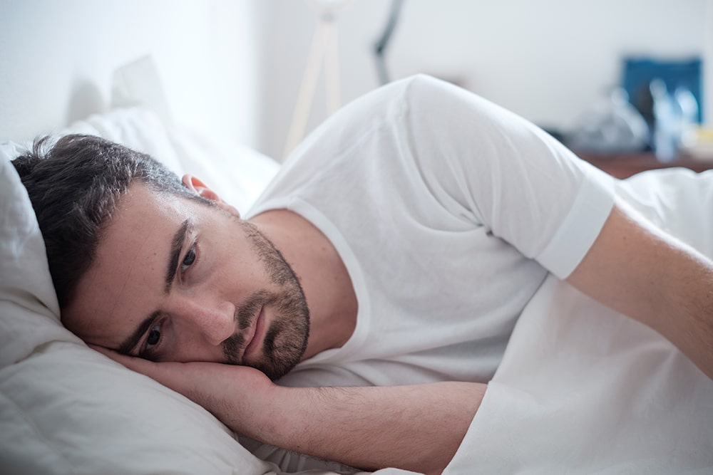 Depressed man laying in bed awake