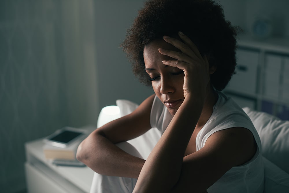 Woman sitting up in bed thinking